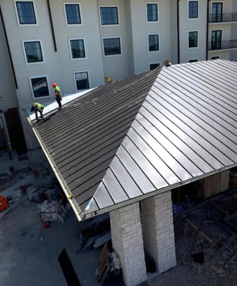 Crew installing standing seam metal roof panels on a commercial project in Lawrenceville